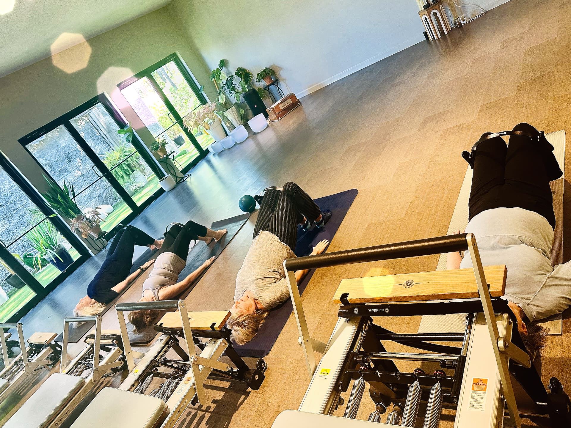 Morning light across the studio floor as clients work through a reformer and mat class