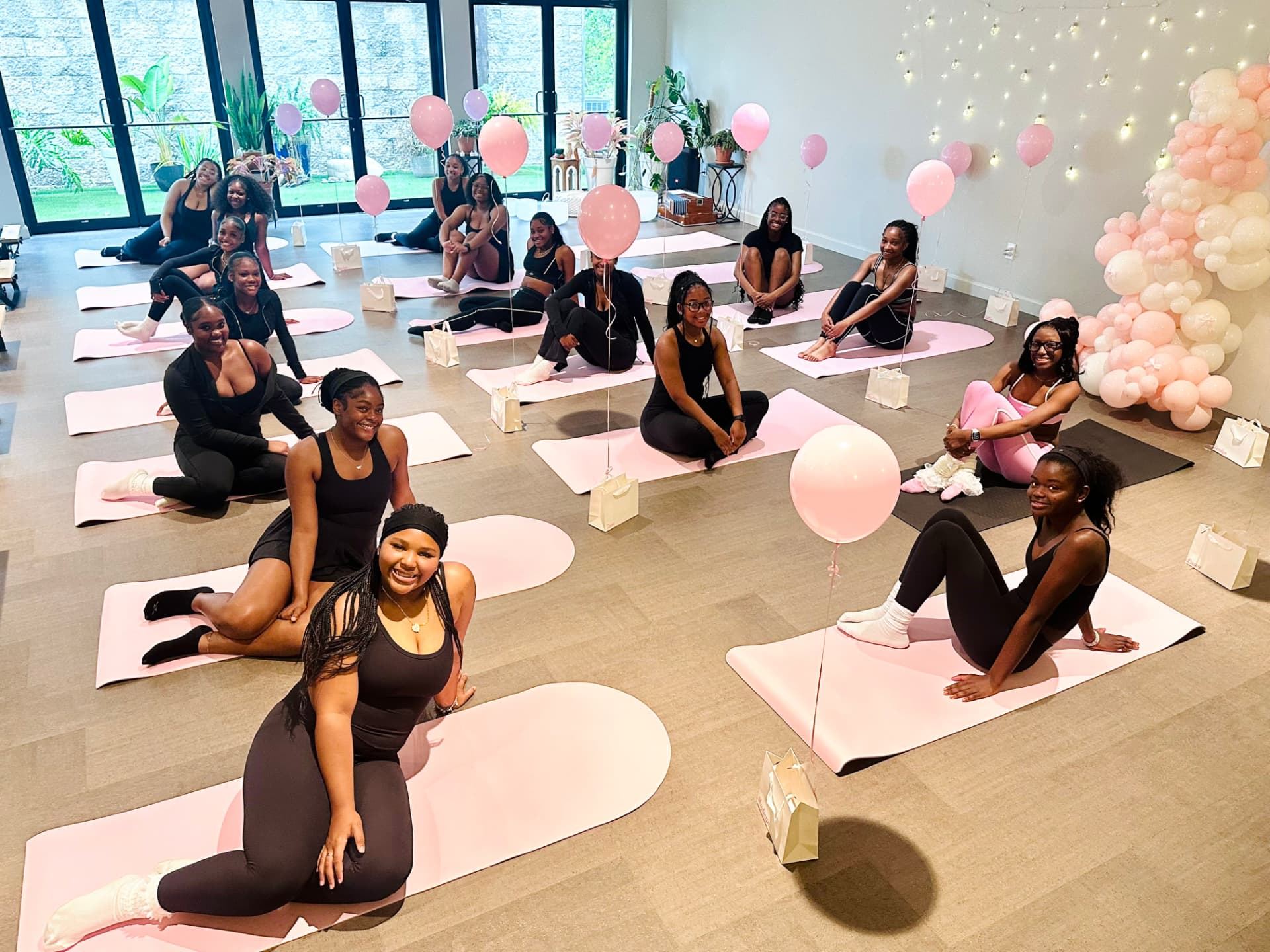 A group of friends smiling together on mats after a private group event in the studio