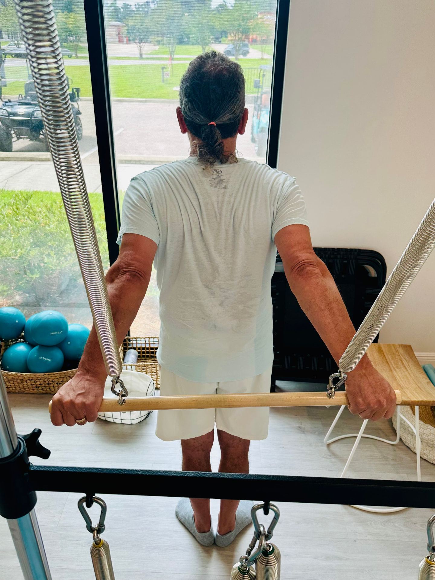 An instructor kneeling beside the reformer to guide a client through a private session